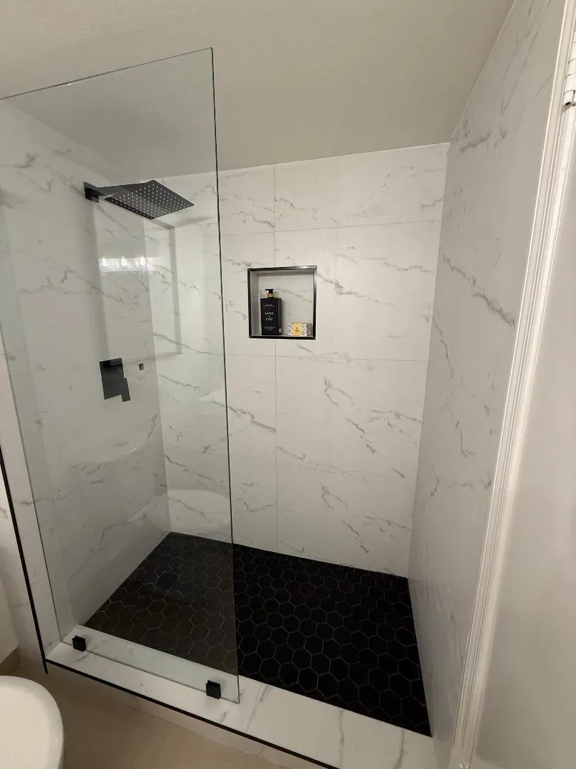 Master bath shower with porcelain file and stone flooring. Rain shower head and hand held sprayer.