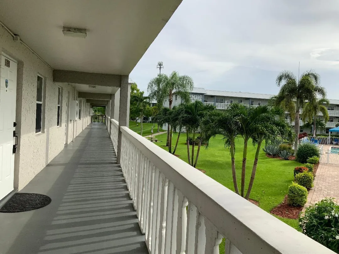 View of front door and catwalk and manicured landscaping