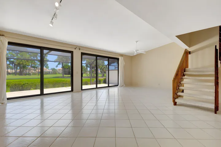 Another view of the living area highlights the tall impact sliding glass doors, screened balcony, and sweeping views of the Champion Golf Course beyond.