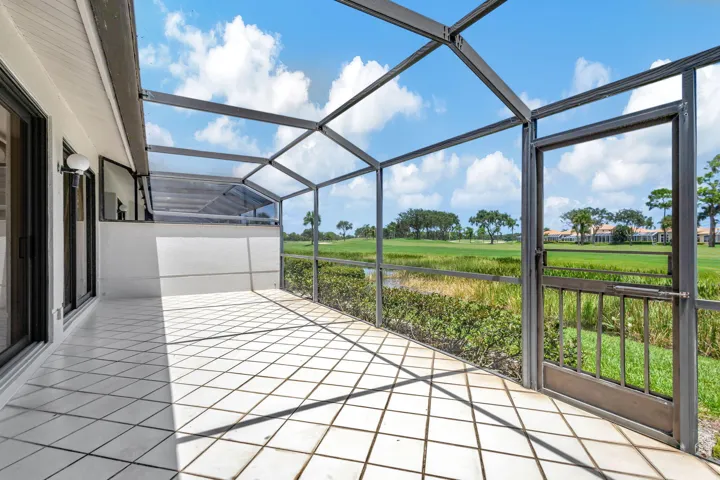 Expansive screened patio with impact sliding glass doors and tile flooring, offering panoramic views of the Champion Golf Course, home of the Cognizant Classic.