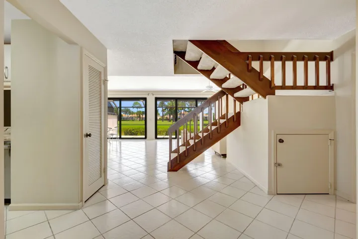 Expansive tiled flooring throughout, featuring a natural wood staircase with balusters