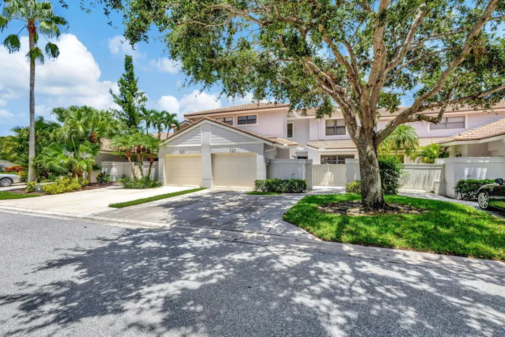 Neutral-toned exterior with a one-car garage, driveway providing additional parking, and a walkway leading to the private gated entry.
