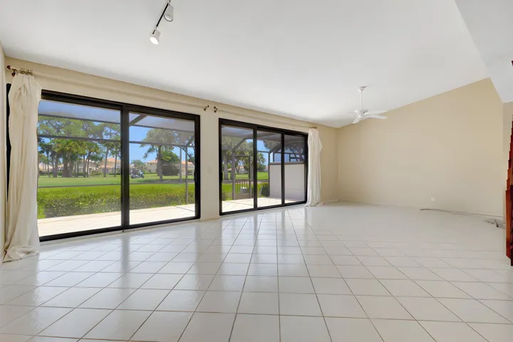 Tall impact sliding glass doors open to a screened-in balcony, showcasing magnificent panoramic views of the Champion Golf Course and providing the perfect setting to enjoy the beautiful golf course scenery.