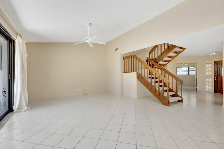 Open living area with tile flooring and a versatile ground-floor room that can serve as a bedroom, den, or home office, conveniently located next to a full bath.