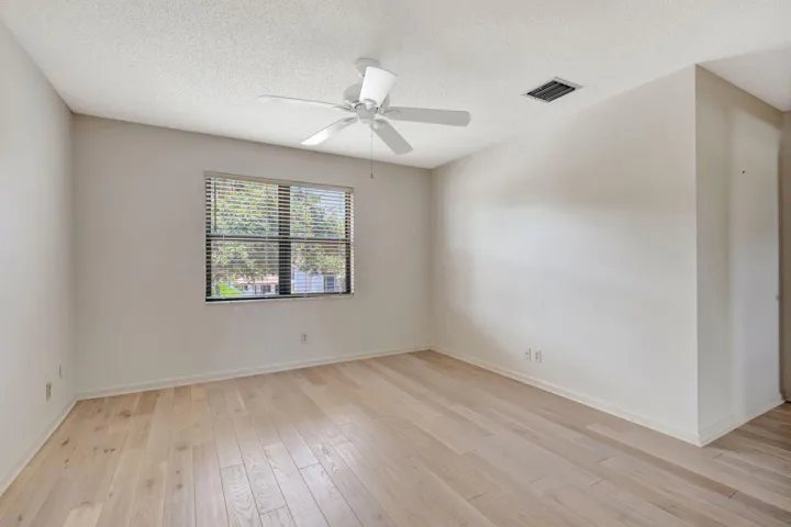 Light wood-finish flooring, a ceiling fan, window with blinds, and white walls