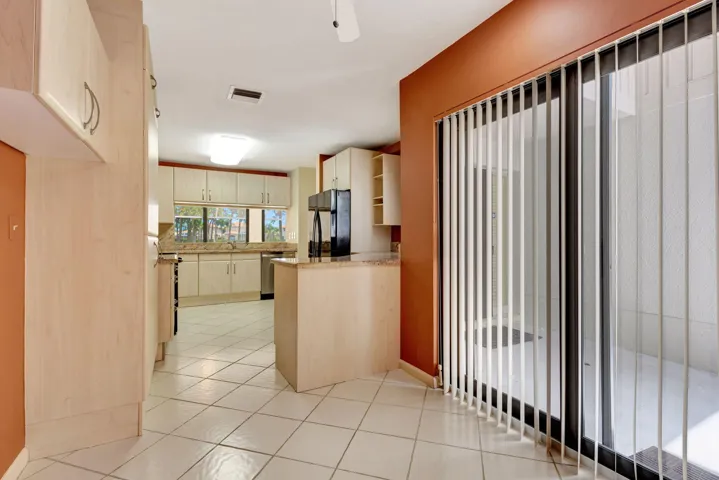 Kitchen featuring light-toned cabinetry, tile flooring, and a sliding glass door with vertical blinds