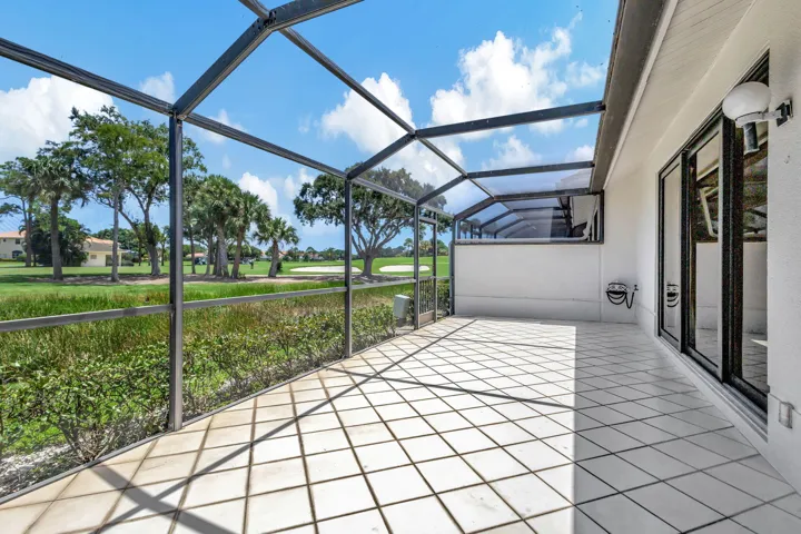 Impact sliding glass doors open to a screened patio with diagonal tile flooring, showcasing magnificent panoramic views of the Champion Golf Course.
