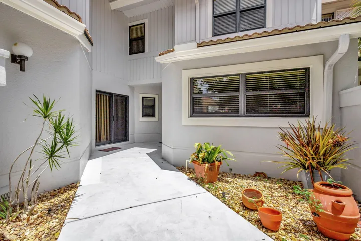 Gated entry opens to a spacious rock garden leading to the front door with decorative wood panels, leaded glass, and a sidelight.