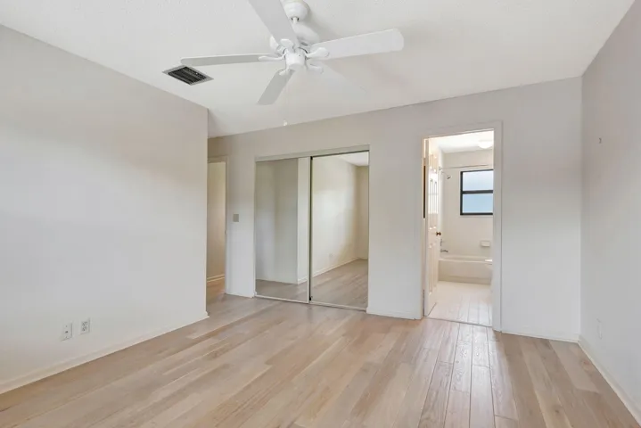Comfortable second bedroom ideal for guests, featuring light wood-finish flooring, a ceiling fan, and a window providing natural light.
