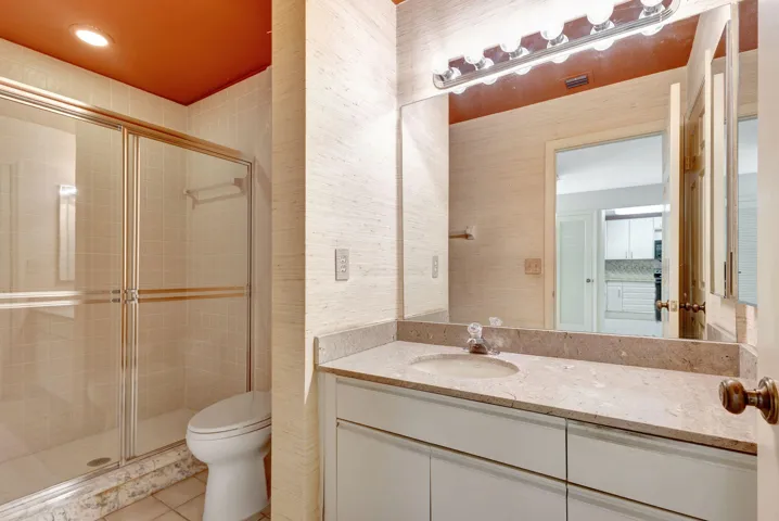 Ground-floor full bath with a tub/shower combination, glass sliding enclosure, attractive vanity, and coordinating mirror.