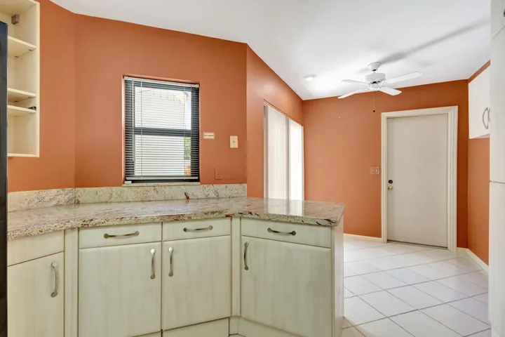 Kitchen featuring light-toned cabinetry, a granite-finish countertop, and tile flooring
