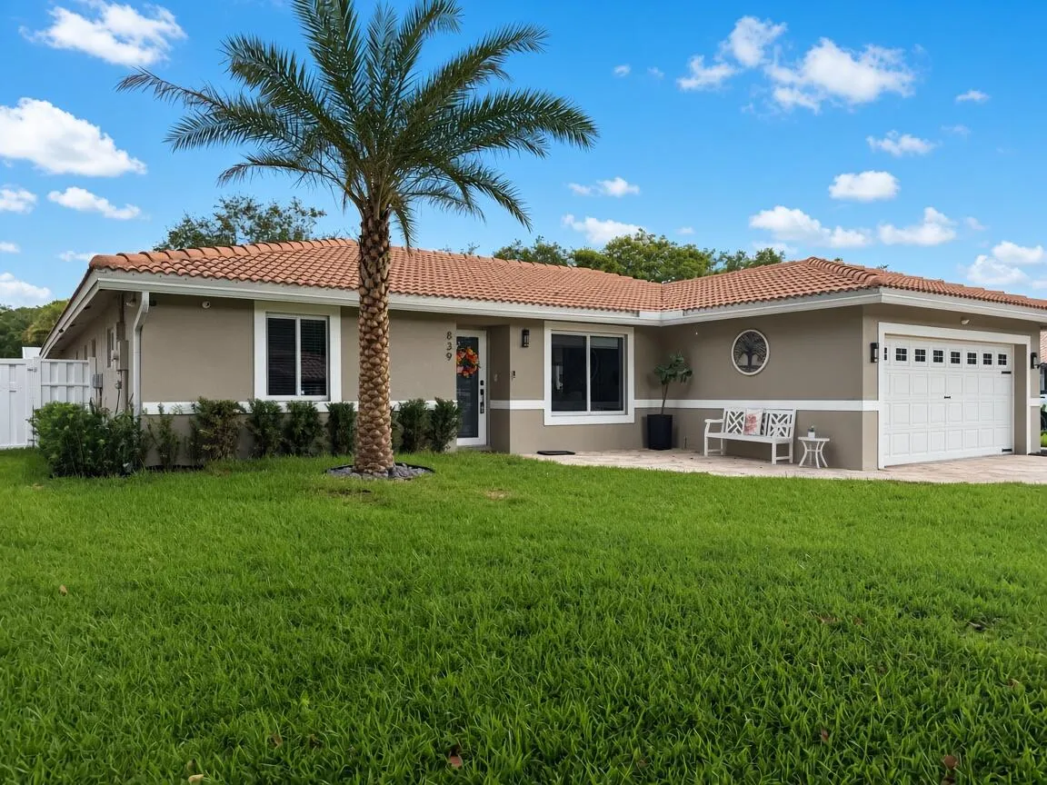 Exterior featuring a tile roof, stucco finish, white frame windows, a single-car garage, and a circular window accent