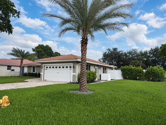 Single-story residence featuring a tile roof, an integrated garage with a white panel door, and a paver driveway