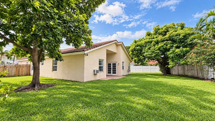 Expansive green lawn with mature trees and a paved patio area