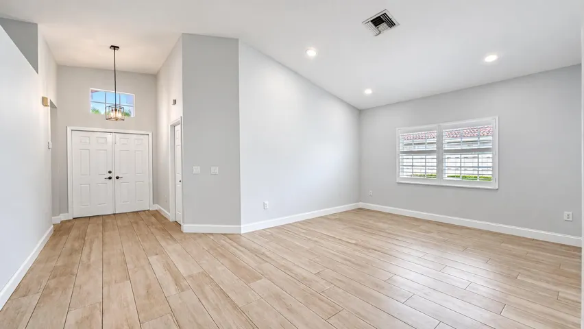 Wood-finish flooring, recessed lighting, double entry doors, high vaulted ceilings, and plantation shutters