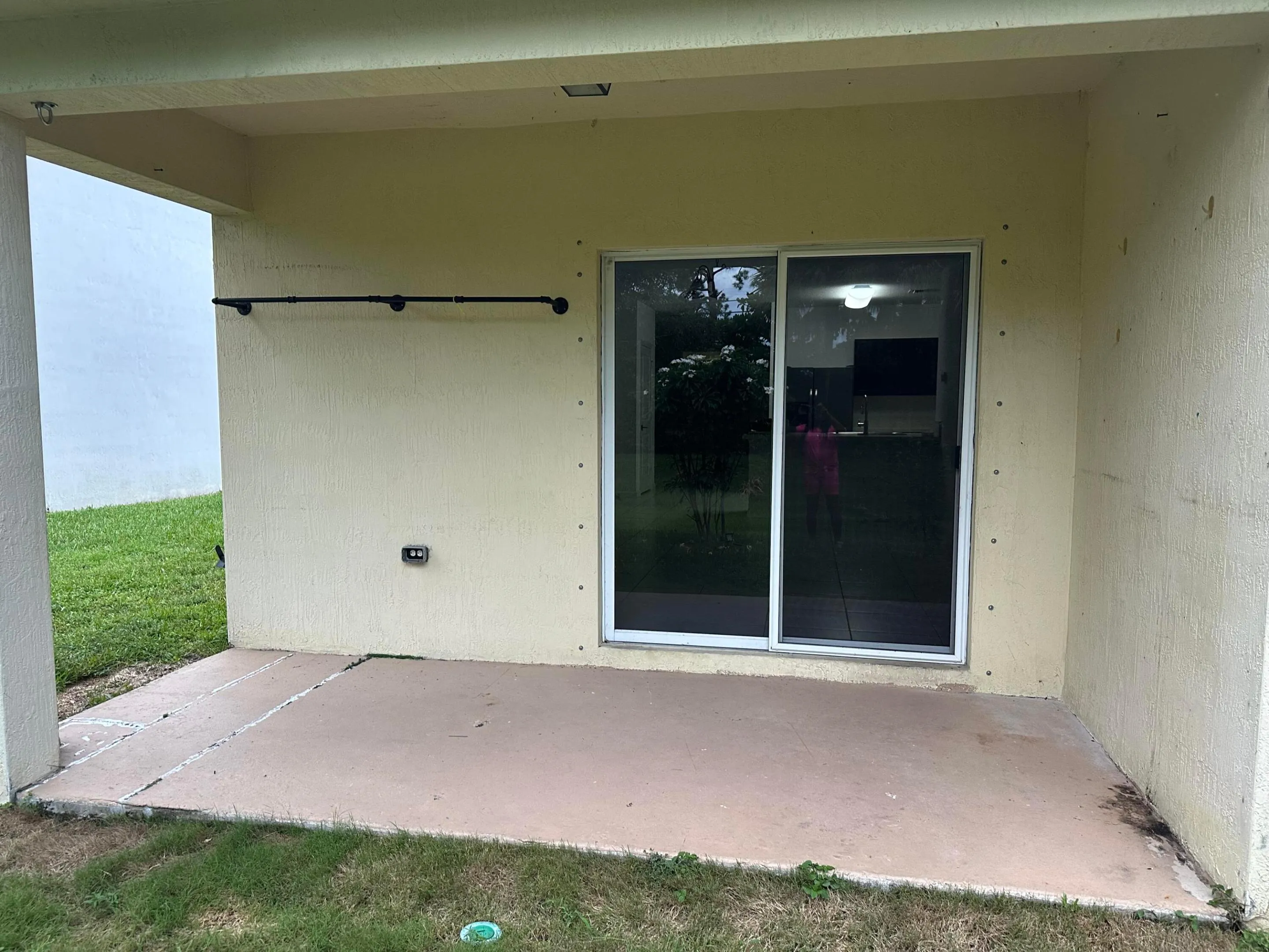 Covered patio with a concrete slab, exterior wall sconce, and sliding glass door