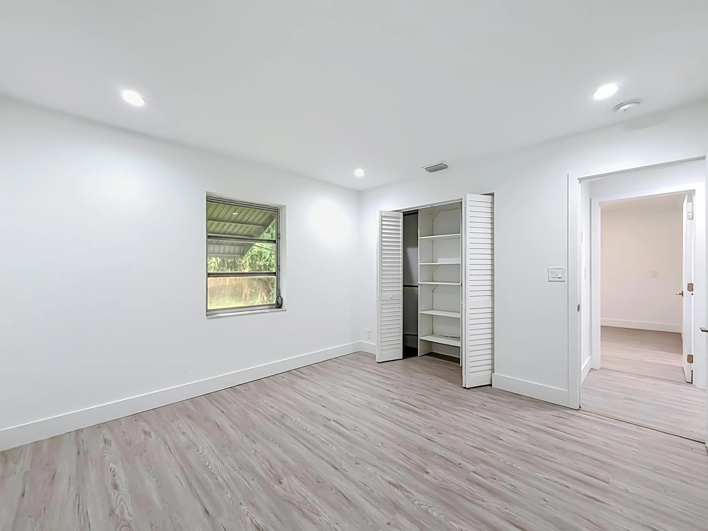 Recessed ceiling lighting, wood-finish flooring, louvered bi-fold closet doors, built-in closet shelving, and a single window