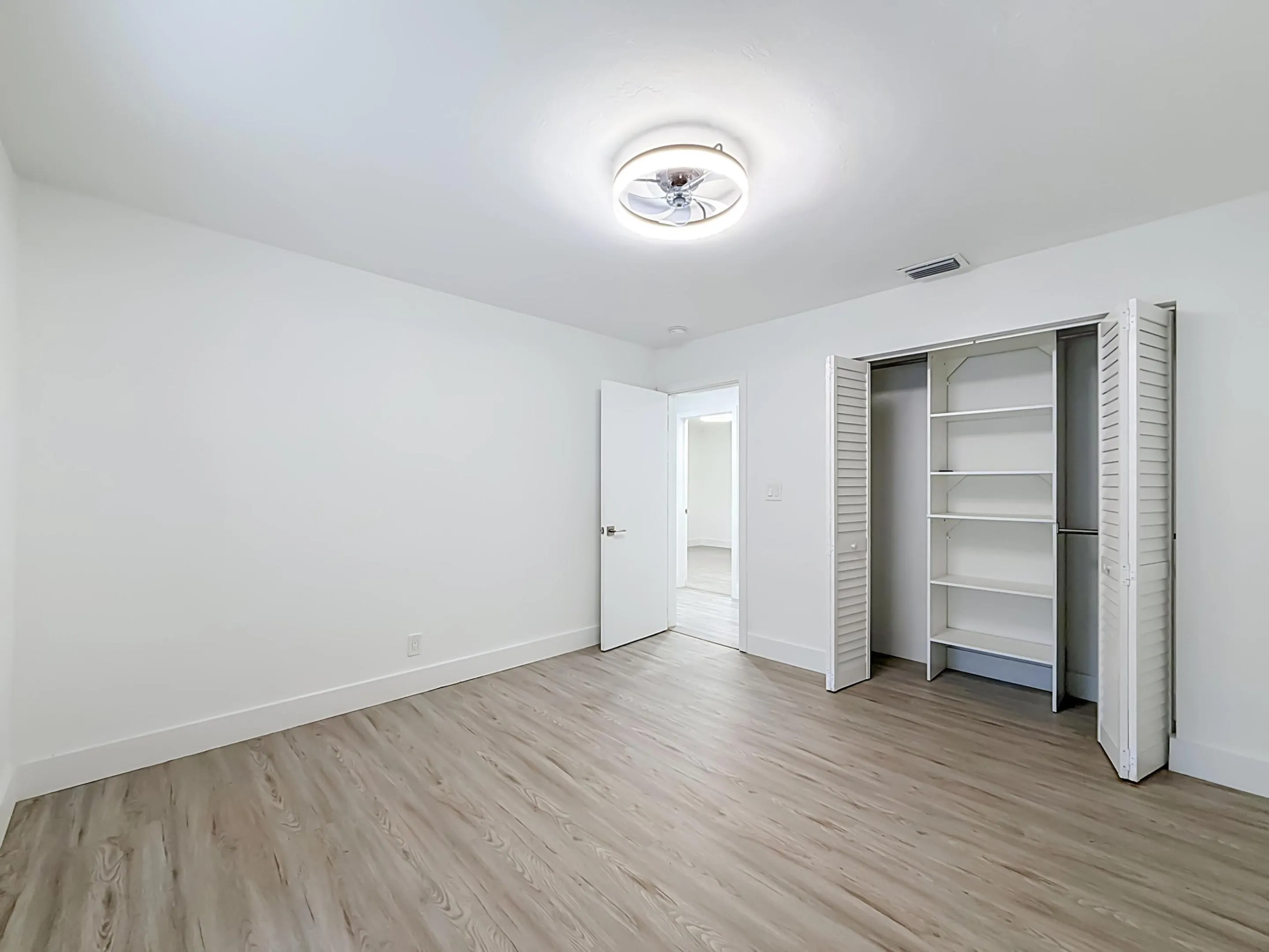 Wood-finish flooring with white baseboards, a built-in closet with shelving, and a ceiling-mounted light fixture