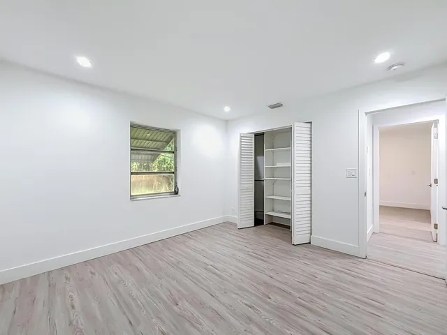 Recessed ceiling lighting, wood-finish flooring, louvered bi-fold closet doors, built-in closet shelving, and a single window