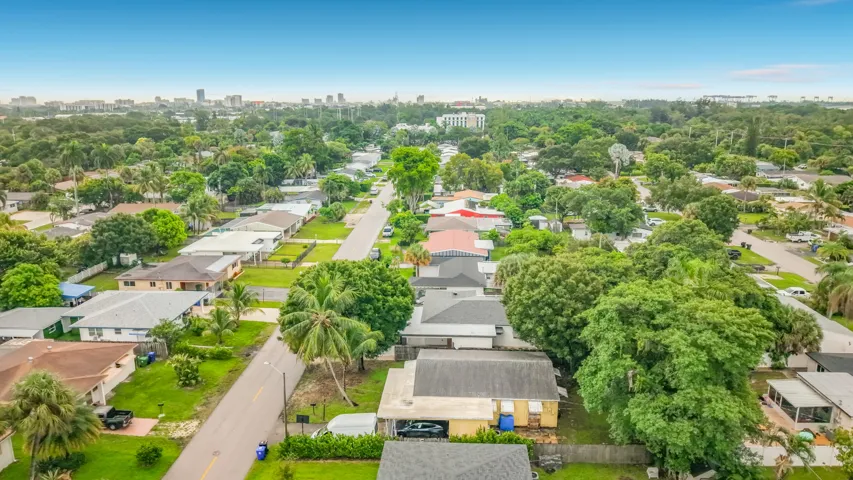Residential street with mature trees and a distant cityscape