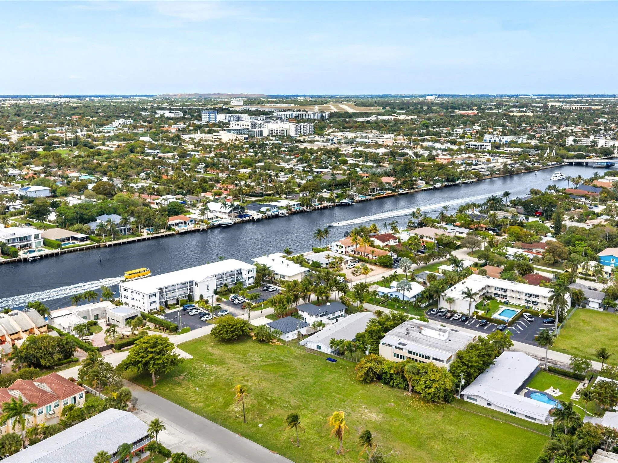 Expansive green lot with established trees, surrounded by residential properties and waterways
