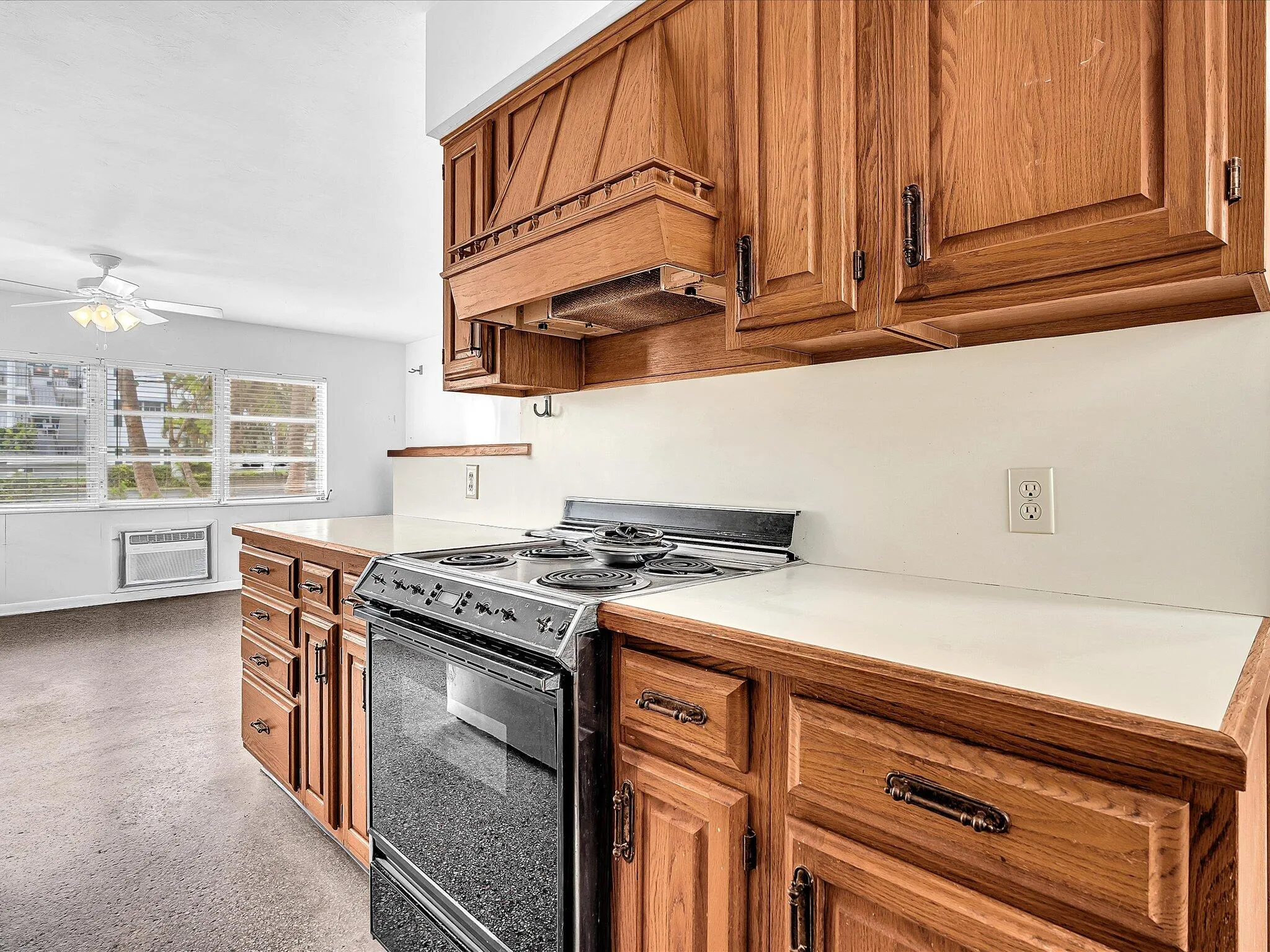 Kitchen featuring wood cabinetry, white countertops, built-in electric range, and white walls