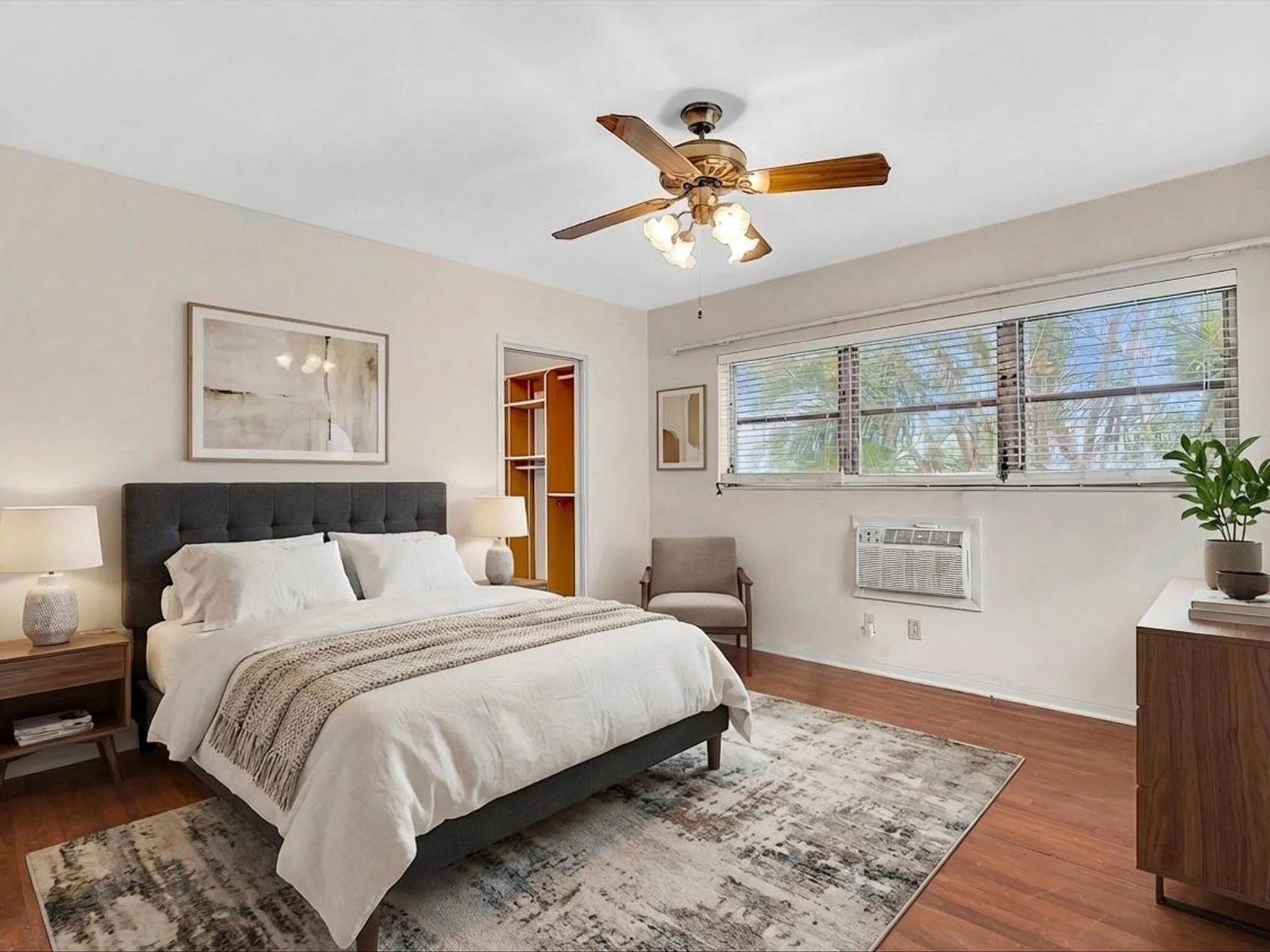 Wood-finish flooring, ceiling fan, window treatments, built-in shelving, and wall-mounted air conditioning unit