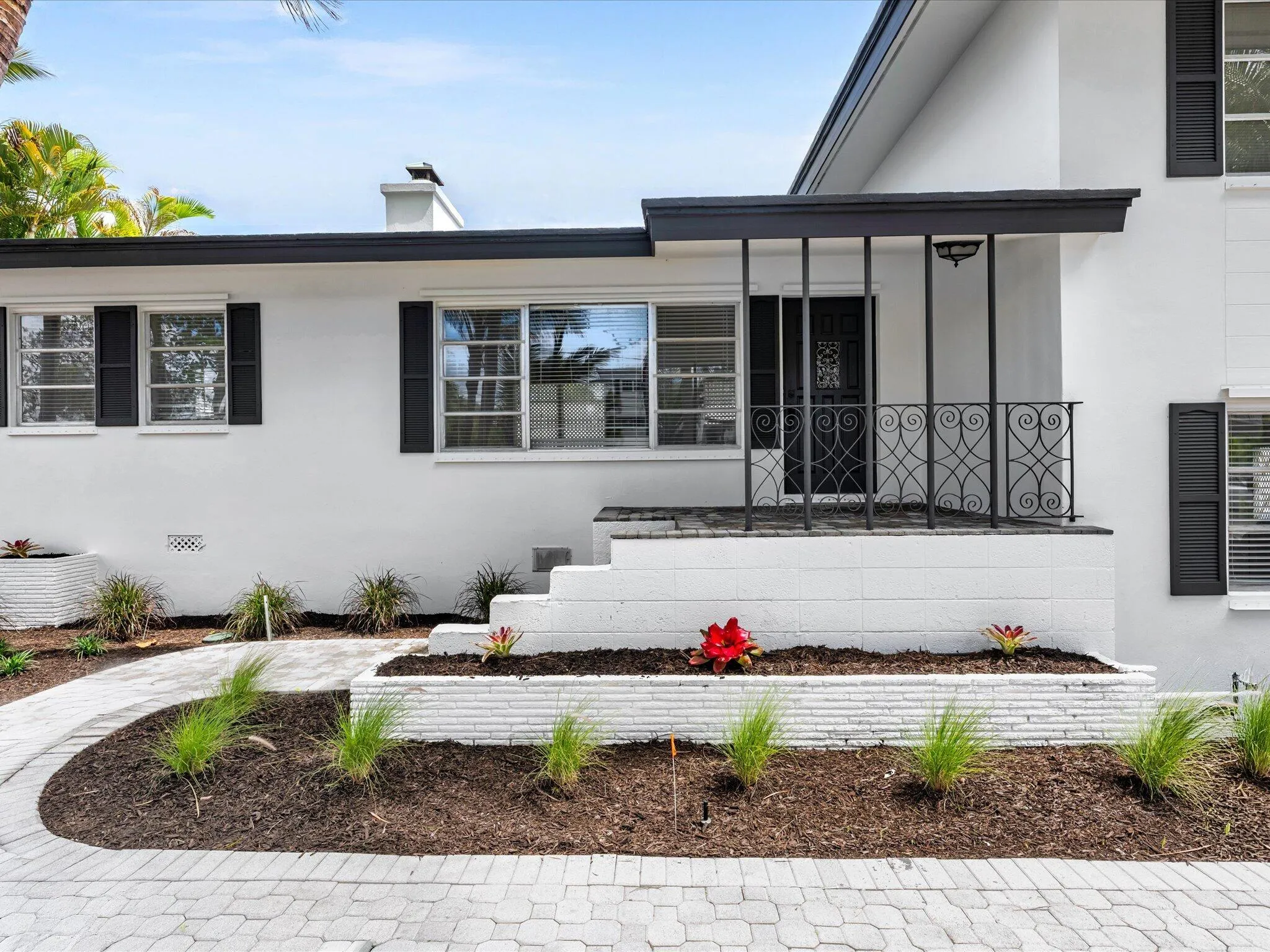 White exterior with black shutters and a covered porch featuring decorative iron railings