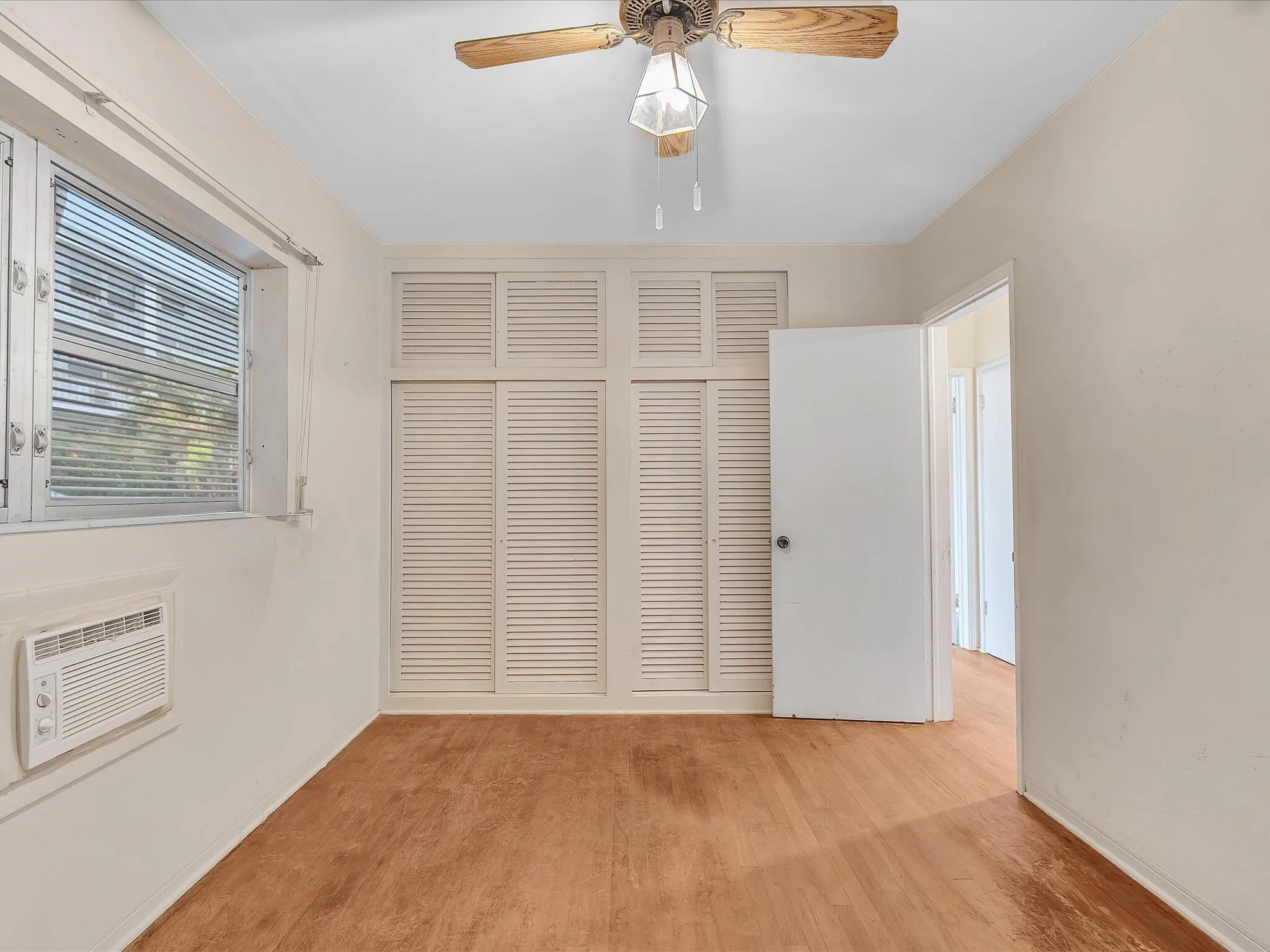 Wood-finish flooring with a window AC unit and a ceiling fan