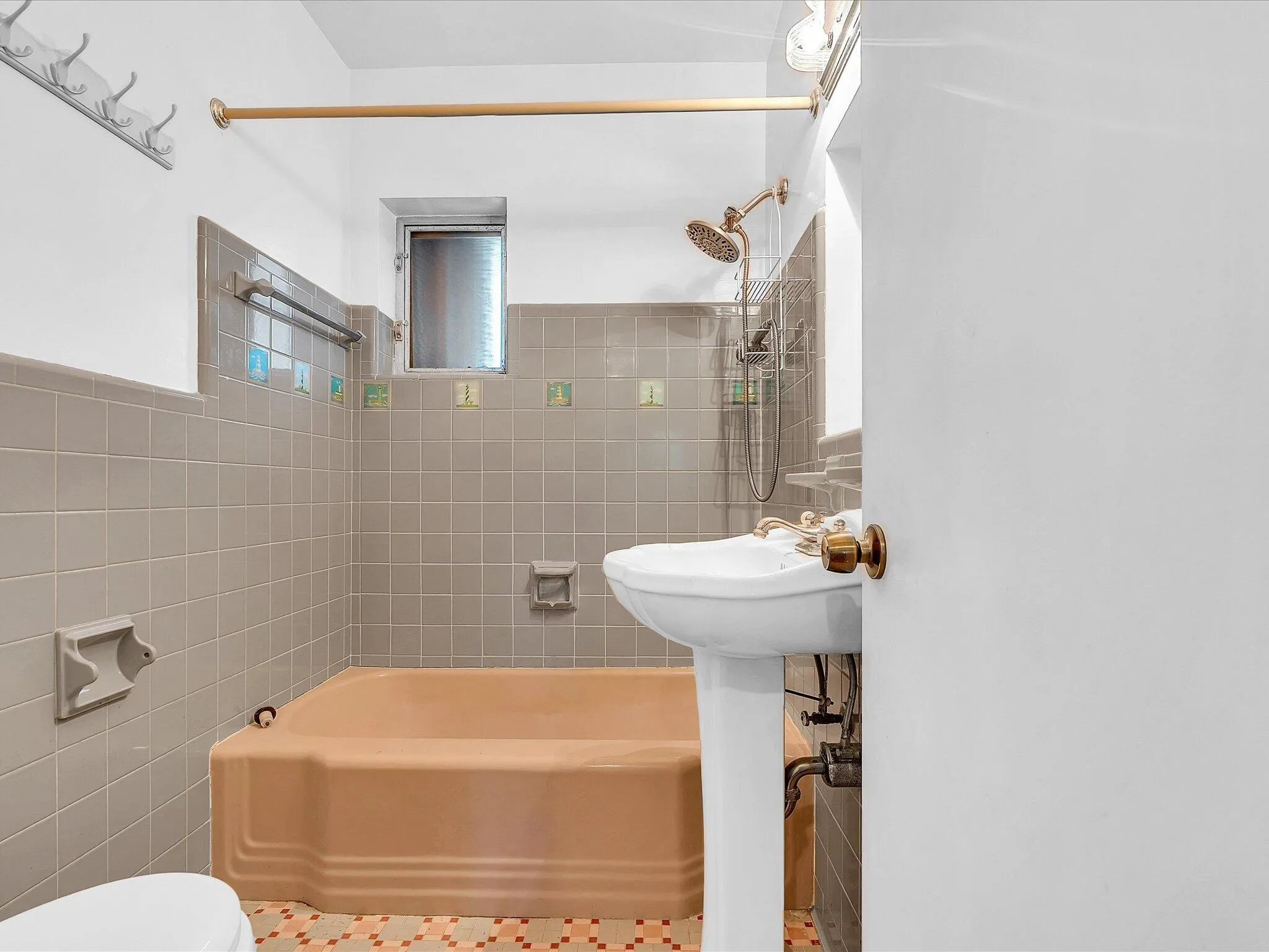 Pedestal sink, shower/tub combination with tiled surround, and mosaic tile flooring