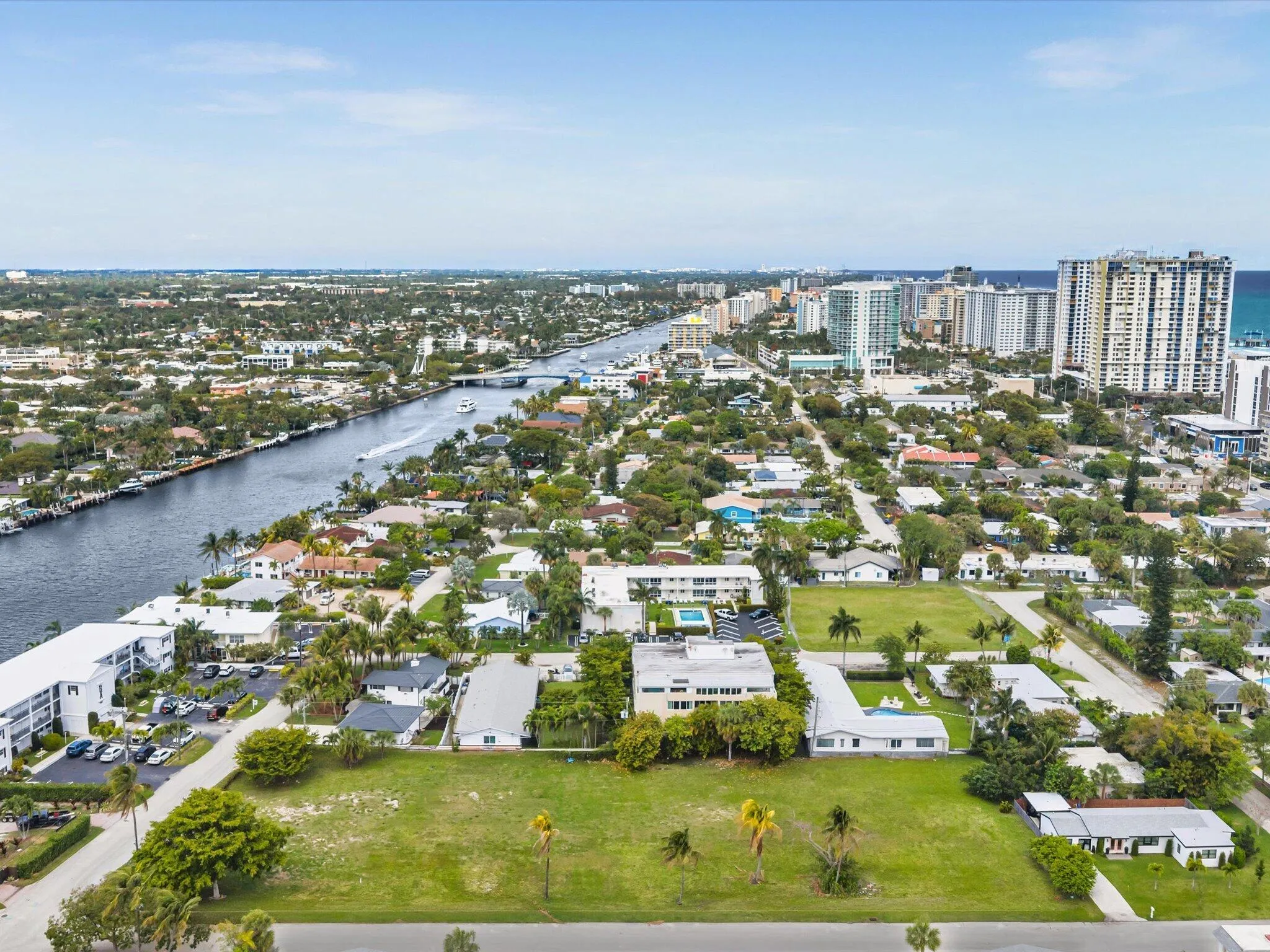 Expansive green space featuring surrounding residential structures, a prominent waterway, and distant high-rise buildings