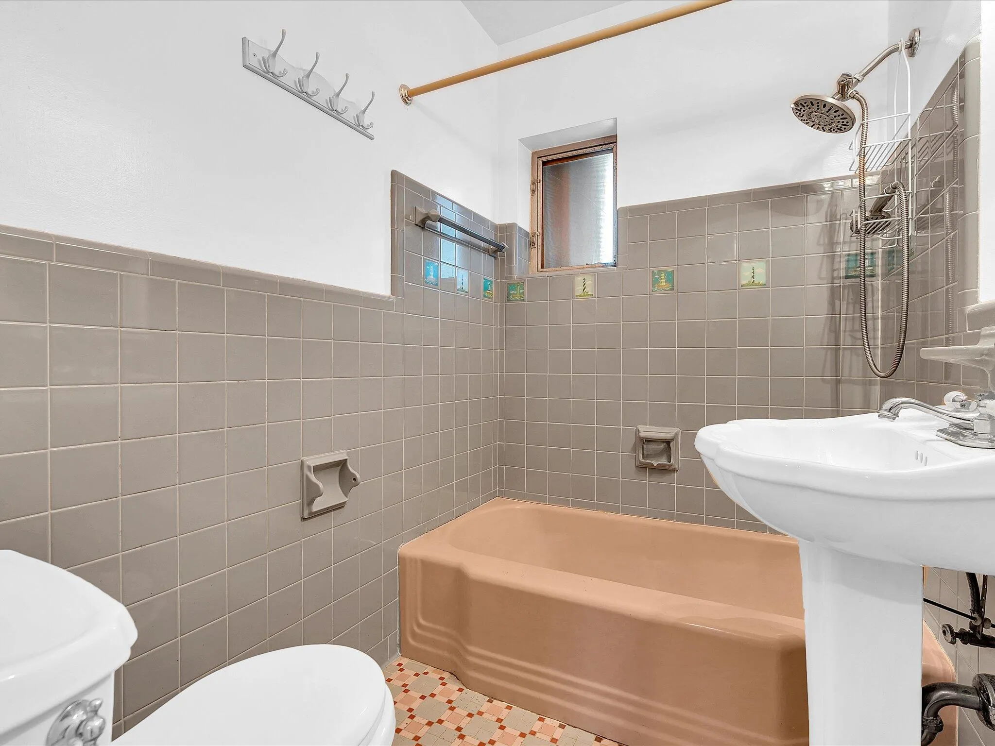 Pedestal sink with chrome fixtures, tiled walls, and a window for natural light