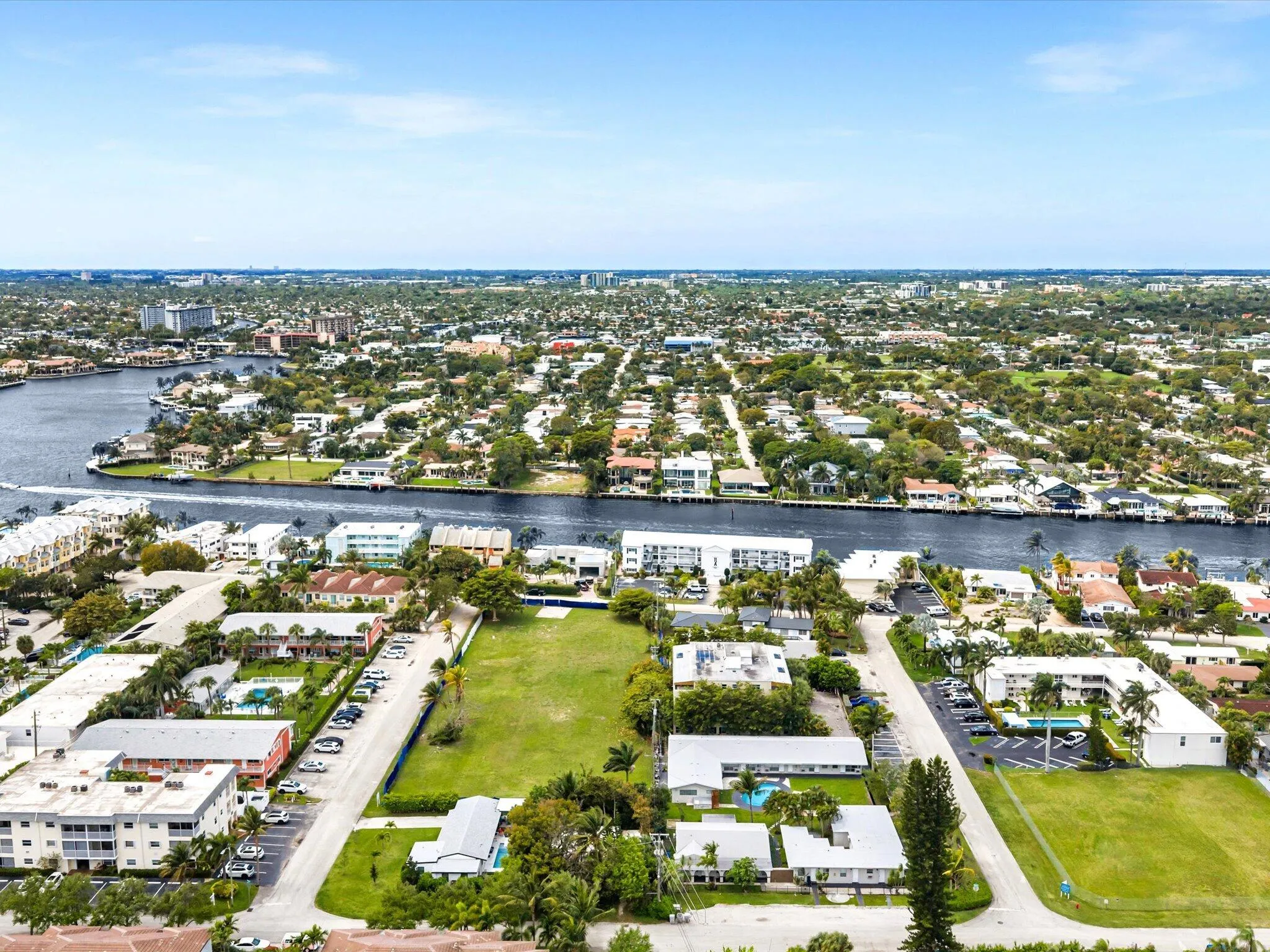 Waterfront properties, diverse architectural styles, mature landscaping, clear blue sky, residential setting