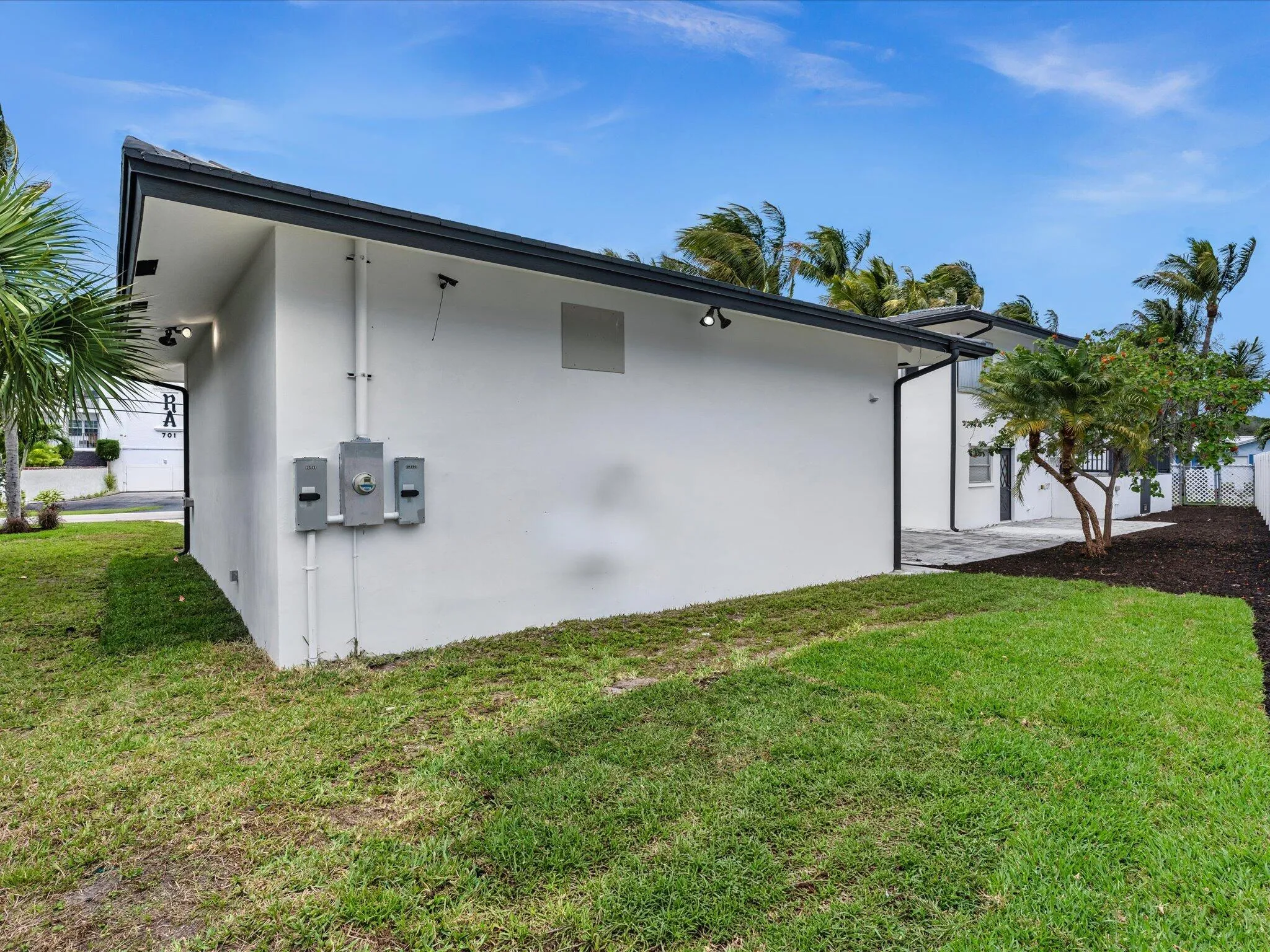 Exterior featuring white stucco finish, dark fascia, and track lighting under the eaves