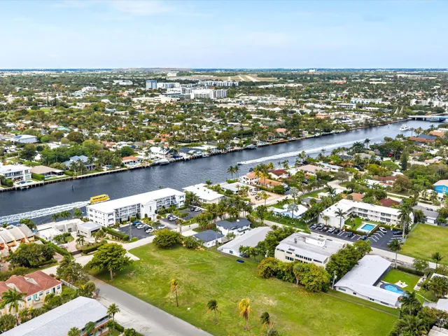 Expansive green lot with established trees, surrounded by residential properties and waterways
