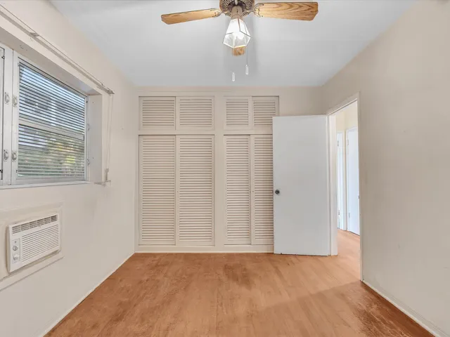 Wood-finish flooring with a window AC unit and a ceiling fan