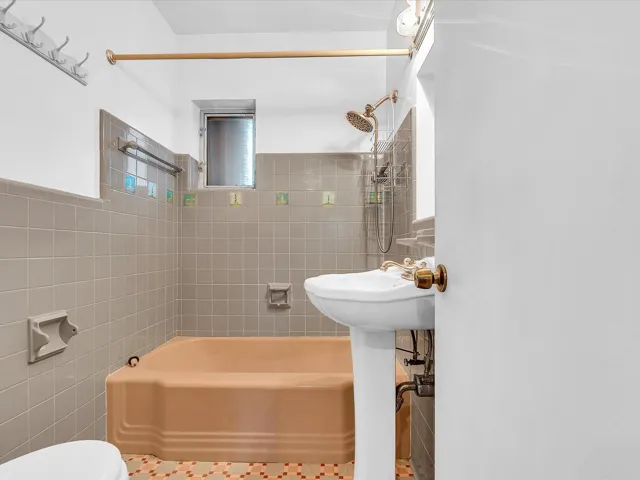 Pedestal sink, shower/tub combination with tiled surround, and mosaic tile flooring