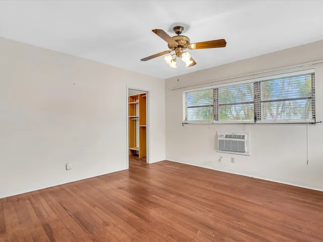 Wood-finish flooring with a ceiling fan light fixture and window air conditioning unit