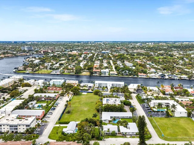 Waterfront properties, diverse architectural styles, mature landscaping, clear blue sky, residential setting