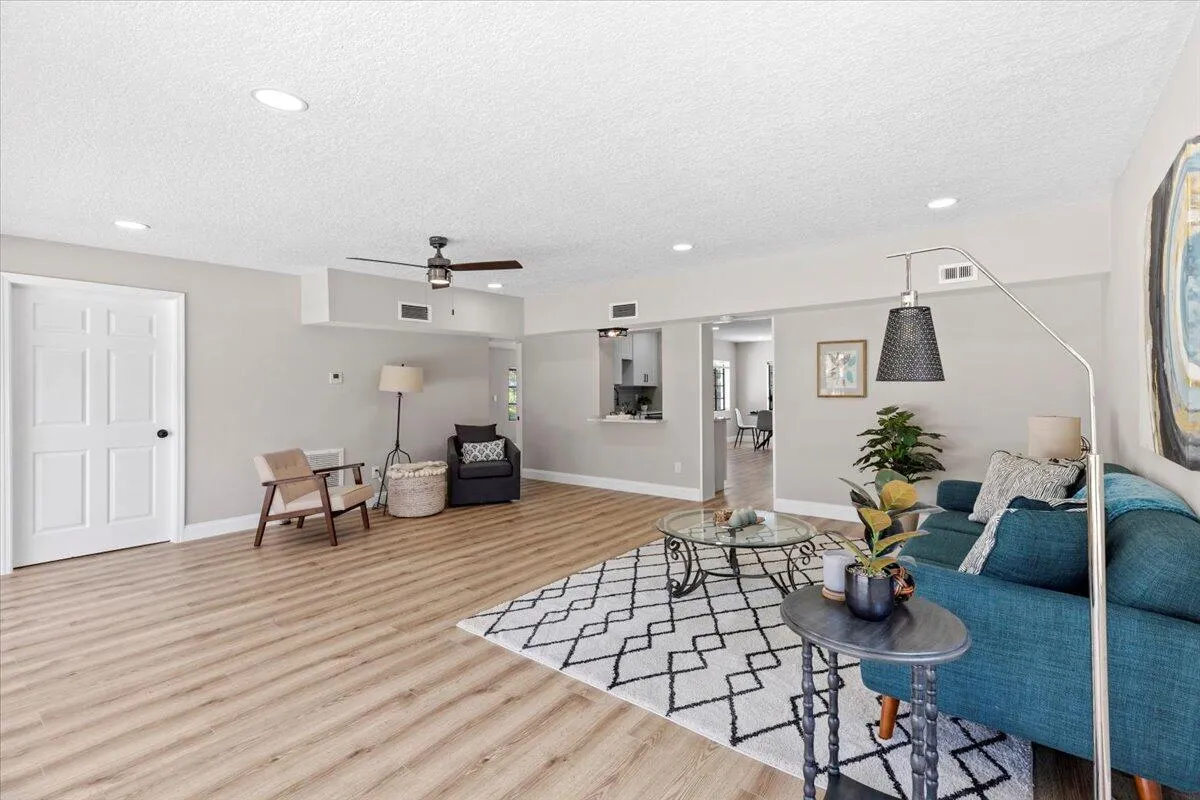 Spacious room featuring wood-finish flooring, recessed lighting, a ceiling fan, and light gray wall tones