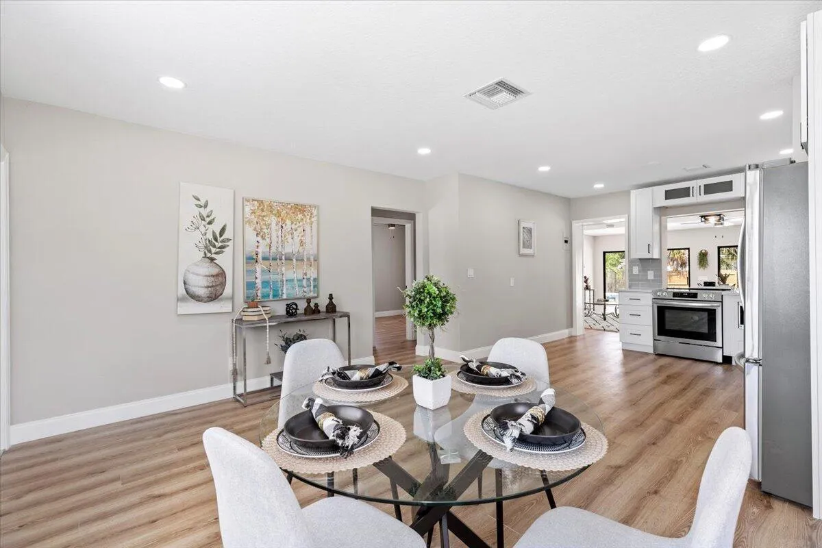 Recessed lighting, wood-finish flooring, white baseboards, and a kitchen with stainless steel appliances and white cabinetry