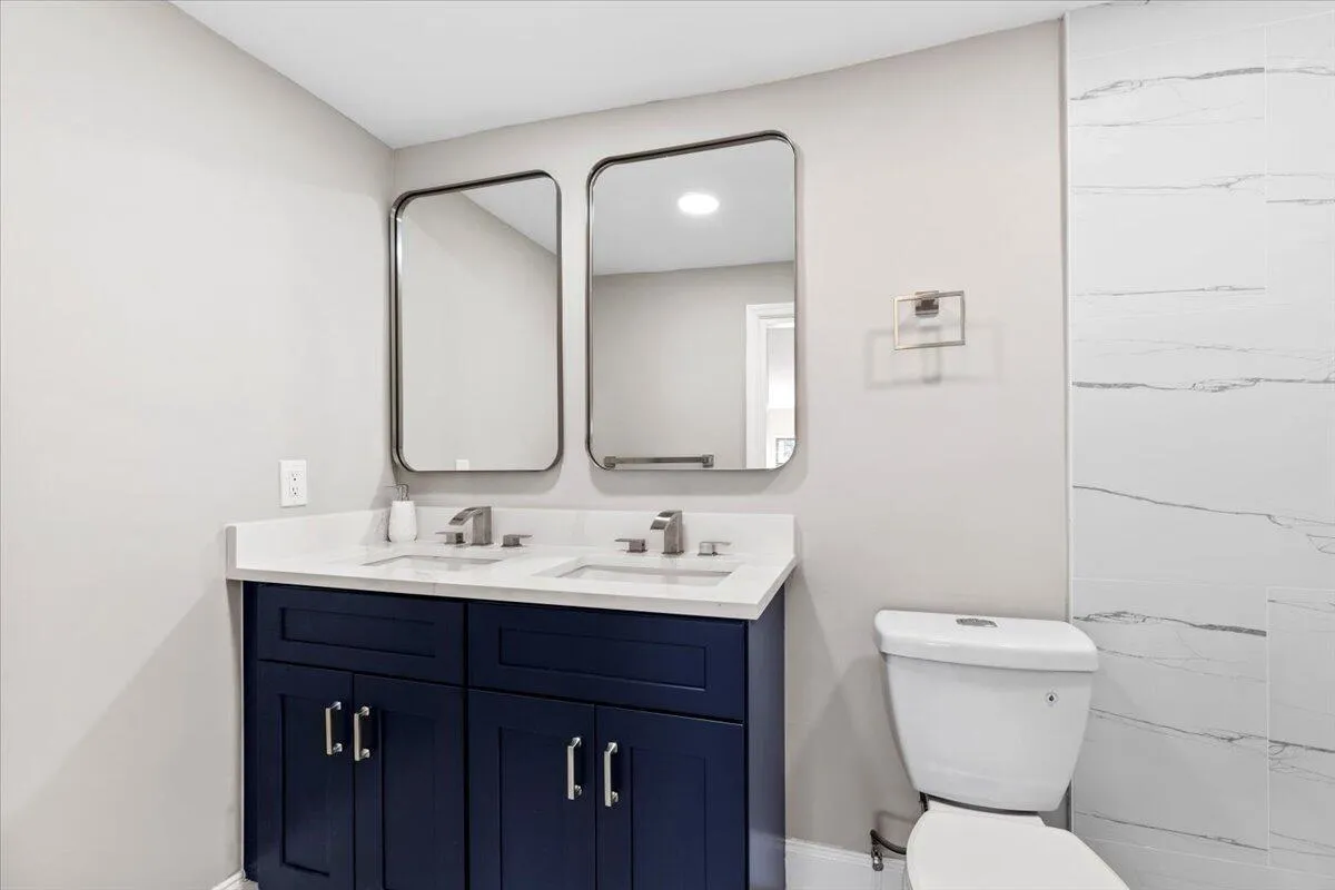 Dual vanity with undermount sinks, white countertop, and dark blue cabinetry