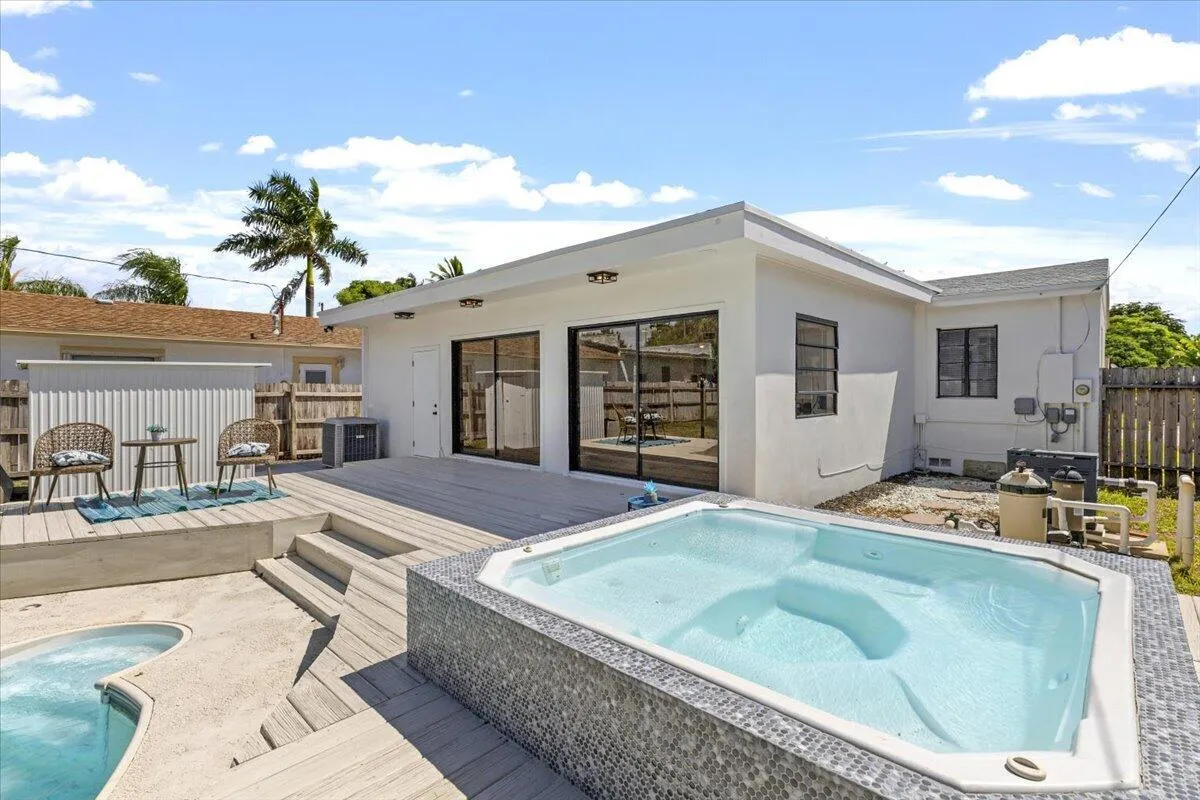 Outdoor spa with mosaic tile surround, spacious composite decking, and direct access to the interior via large sliding glass doors