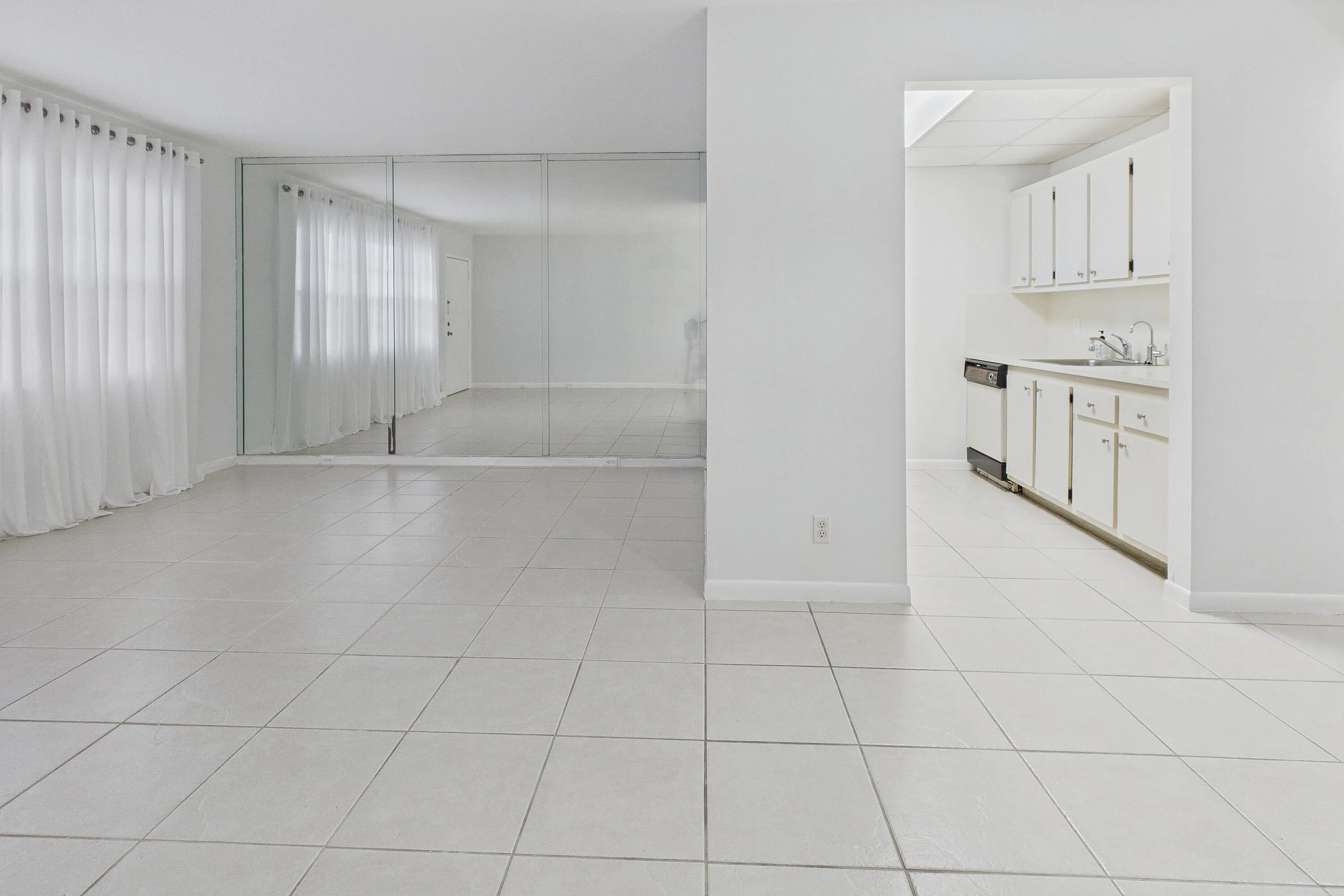 Expansive tiled flooring throughout, mirrored wall, and sheer window treatments
