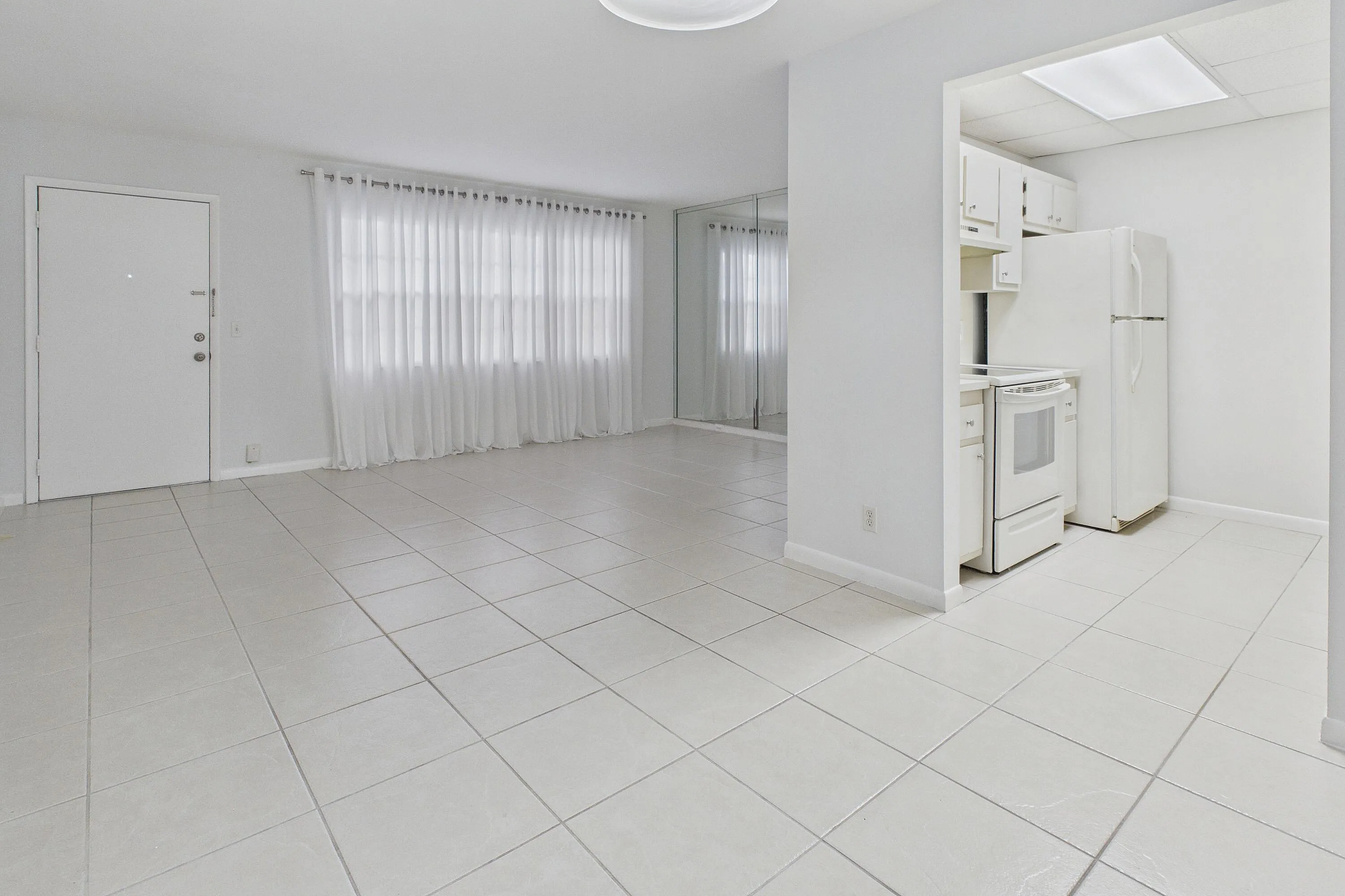 Tile flooring throughout, white kitchen cabinetry, white appliances, and a rectangular ceiling light fixture