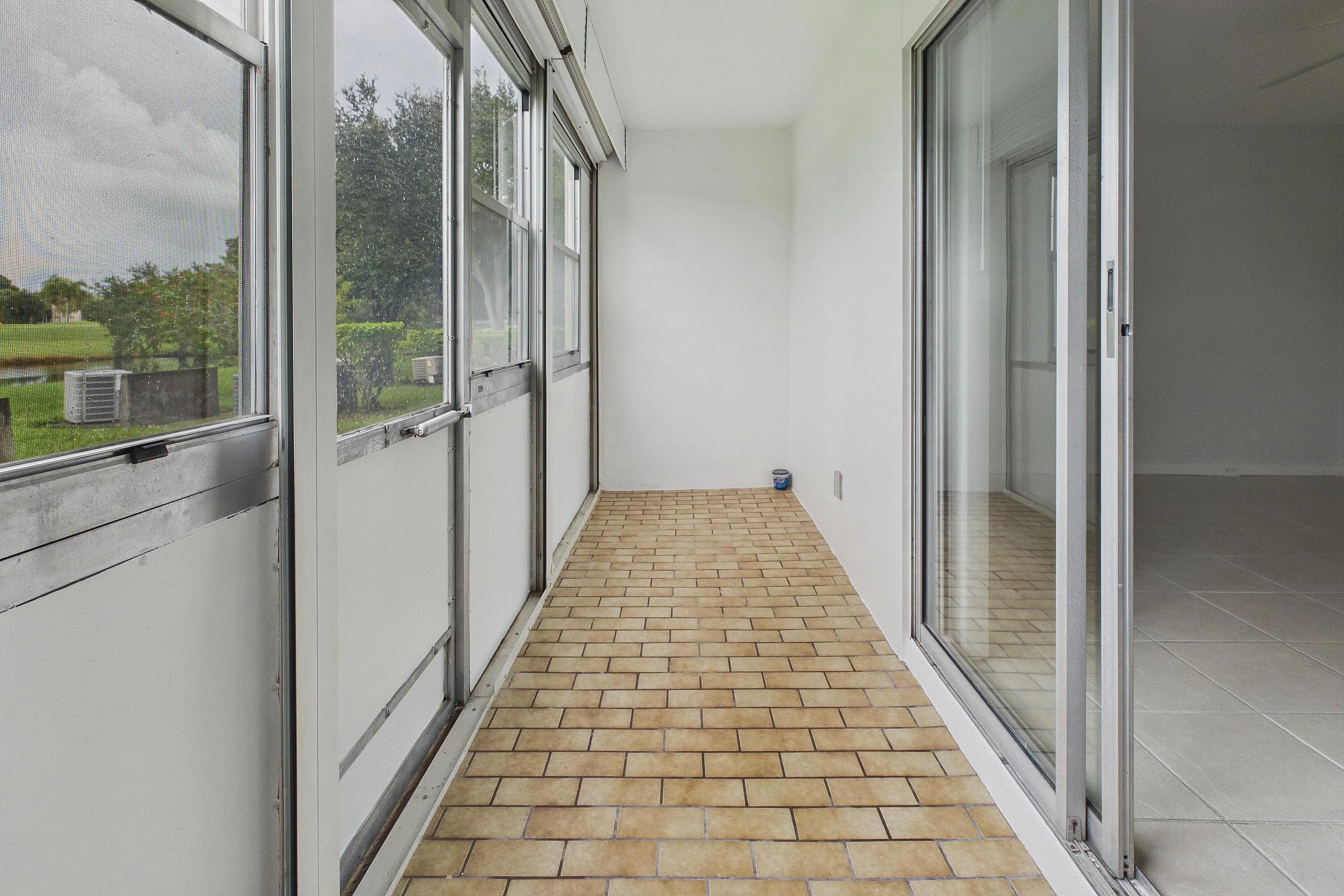 Enclosed and covered patio with brick-patterned flooring and a sliding glass door