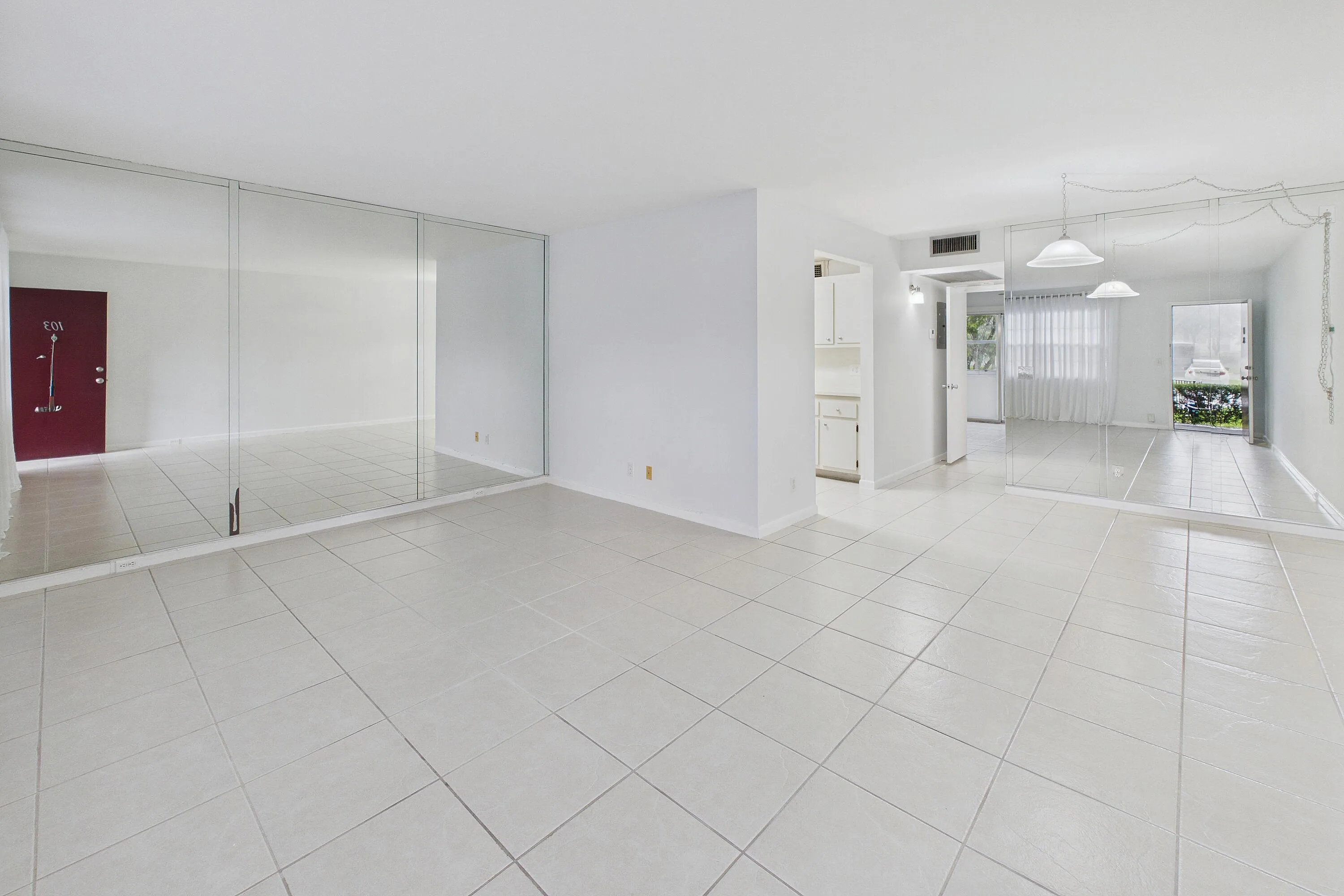 Spacious main living area featuring light-toned tile flooring, and mirrored accent walls.
