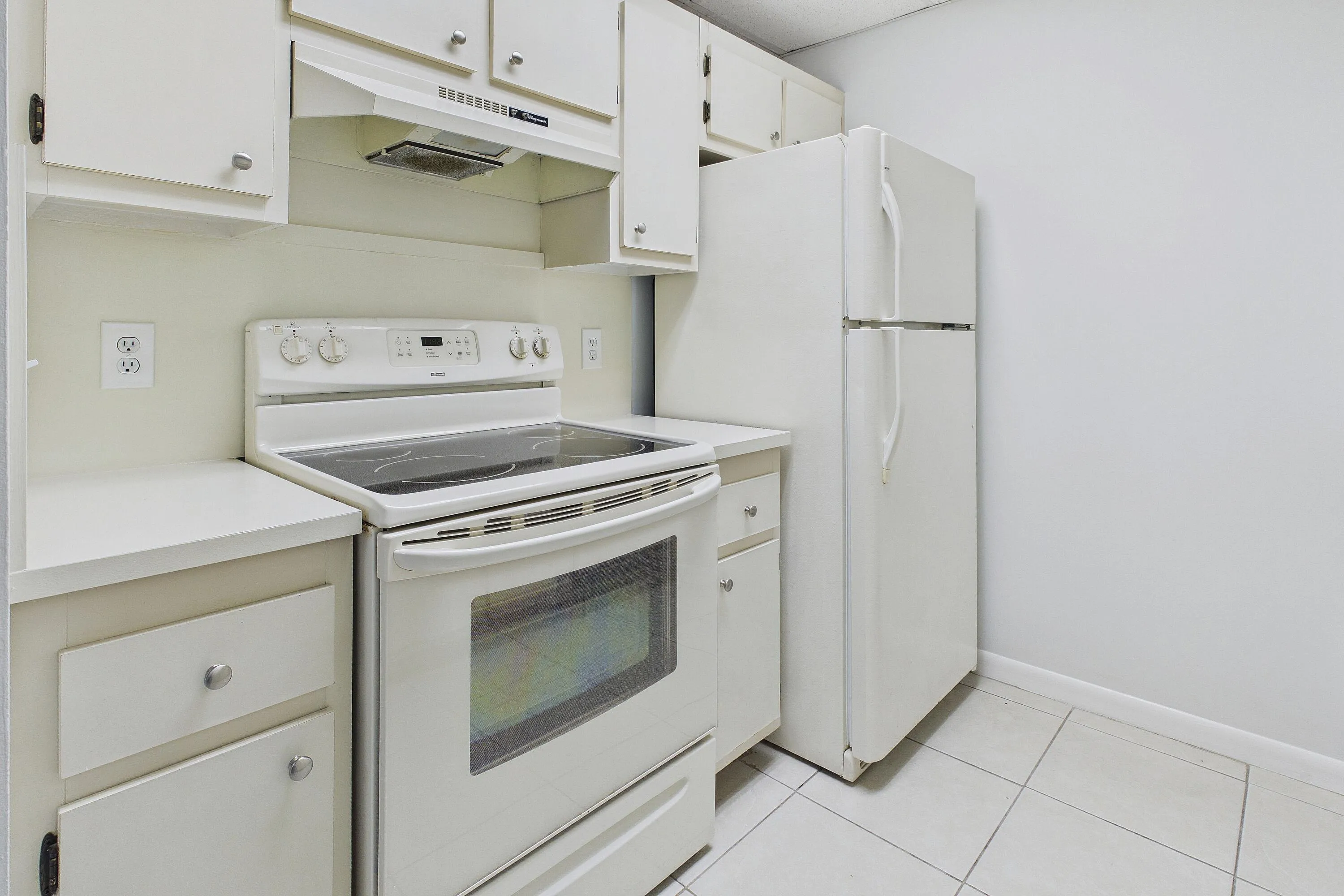 Kitchen featuring white cabinetry, solid surface countertops, white refrigerator, electric range, and tiled flooring