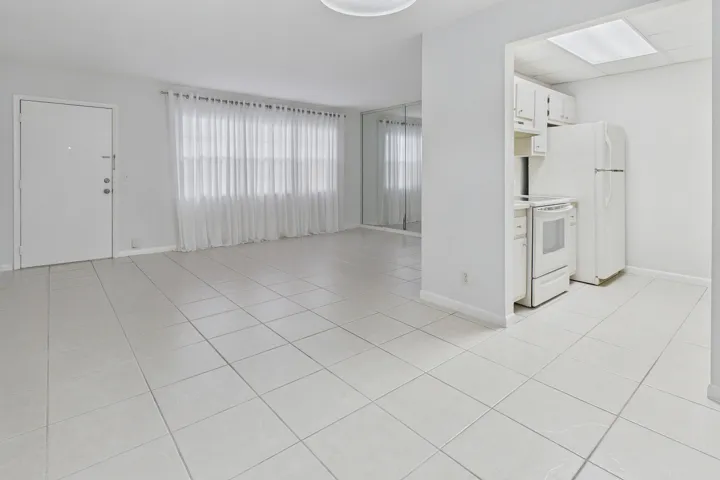 Tile flooring throughout, white kitchen cabinetry, white appliances, and a rectangular ceiling light fixture