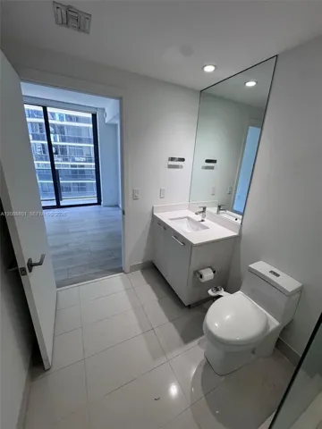 Modern vanity featuring a light-toned wood-finish cabinet, integrated countertop, rectangular basin, and a full-height wall mirror